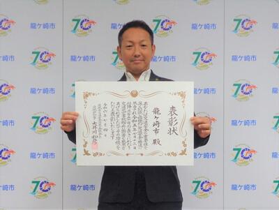市長が表彰状を持っている写真
