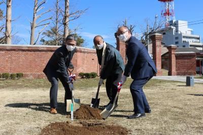 植樹式で土にスコップを入れる3人