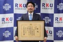 賞状を持つ中原教授の姿
