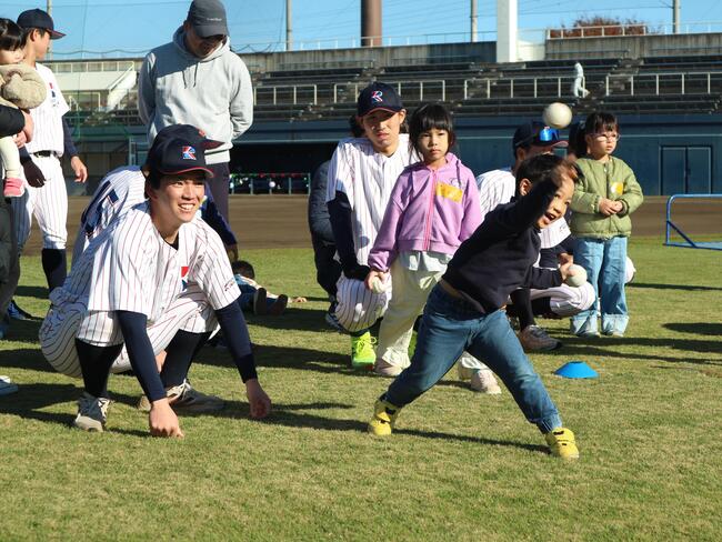 大学生に見守られながら遠くまで投げようとする子どもの様子