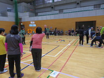 試合で女性がボールを投げ、仲間が見守っている