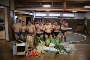 差し入れの商品と力士の皆さんで集合写真